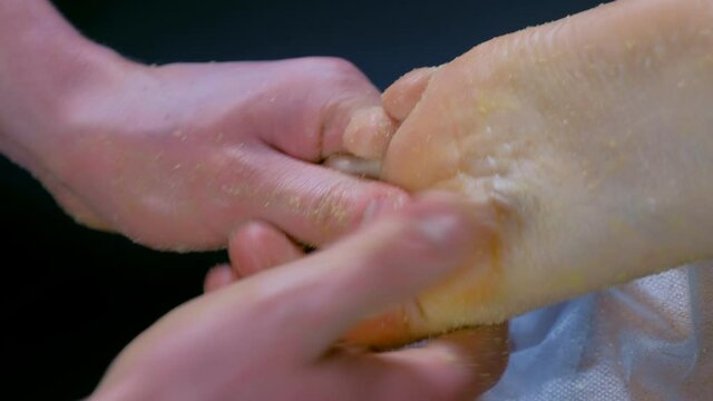 Massagist scrubbing woman's feet with natural scrub in spa salon. Procedure of peeling body for young girl in cosmetology clinic, closeup. Hands massaging client leg. Skincare and bodycare concept.