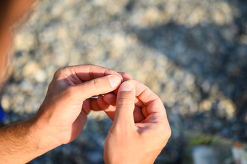 men's hands tying a fishing line on a fishing hook. selective focus. step 4