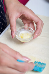 A woman greases puff pastry with butter. For making puff pastry curls with poppy and walnut filling.