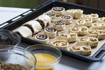 On a baking sheet are curls stuffed with poppy and walnuts. For baking. Nearby ingredients for cooking.
