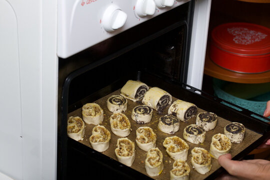 A woman puts curlicues stuffed with poppy and walnuts in the oven. For baking.