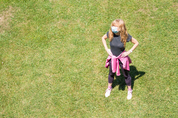 woman with medical mask doing gymnastics on the grass, new normal concept