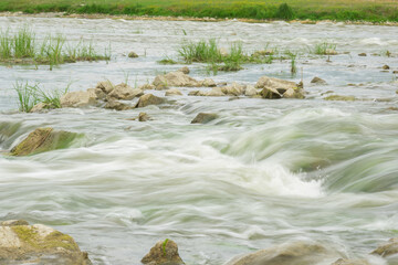 The flow of the river in the summer forest. Stones washed by water. Reflection on the water. water movement for a long exposure.