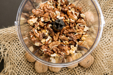 Tasty walnut kernels plastic container of a small kitchen blender. for a tasty dessert.