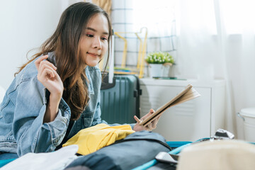 Obraz premium young pretty woman hipster traveler thinking and checking and packing clothes into suitcase for holiday vacation on bed at home, long weekend, summer holiday, backpacker, travel and lifestyle concept