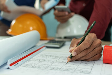 group of professional architect or interior designer hands drawing with pencil on blueprint on desk in meeting room office at construction site, construction industrial, engineering business concept