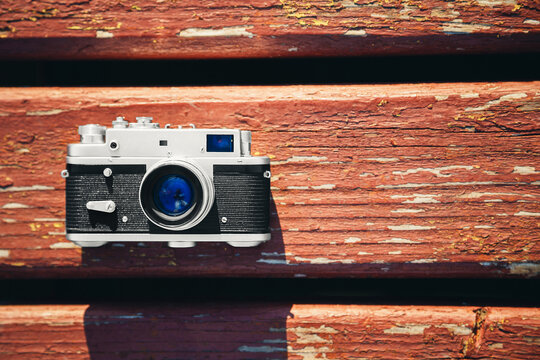 Old vintage film photo camera lying on wooden background. Copy space. Top view