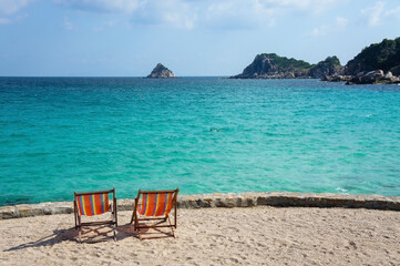 Two bright colored sun loungers against the backdrop of the turquoise sea and rocks. Tailand, Ko-Tao