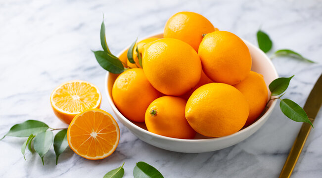 Fresh Meyer lemons in white bowl. Marble background. Close up.