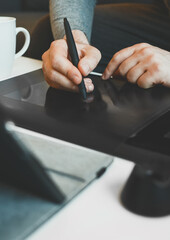 Graphic designer using electronic drawing tablet at home.