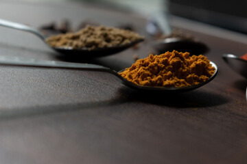 Indian Garam masala powder in bowl and it's ingredients colourful spices. Served over moody background. selective focus