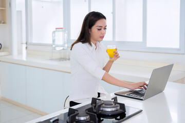 Woman works with laptop while drinks orange juice