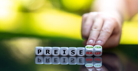Hand dreht Würfel und ändert den Ausdruck "Preise rauf" in "Preise runter".
