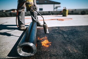 Professional workers insulating rooftop with bitumen membrane. Waterproofing details at construction site. Bituminous membrane waterproofing system details and installation on flat rooftop. - 367833946