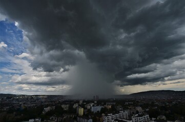 Heavy rain together over Zurich Switzerland with gray storm clouds and blue sky