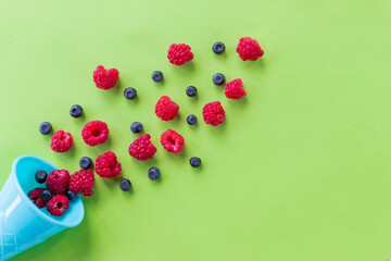 Explosion of different berries. Flat lay with blueberry and raspberry in plastic waffle cone on bright background. Top view. Fresh summer berries in a colorful waffle horn.summer food concept