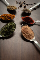 Indian Garam masala powder in bowl and it's ingredients colourful spices. Served over moody background. selective focus