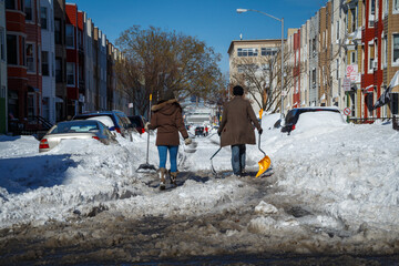 Two people walking down a snowy street in Brooklyn