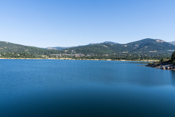 Fototapeta na wymiar Lake from a reservoir surrounded by green mountains in Navacerrada