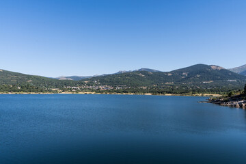 Fototapeta na wymiar Panoramic view of the lake and mountains from a water reservoir in Navacerrada