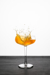 A splash of an orange cocktail in a coupe glass