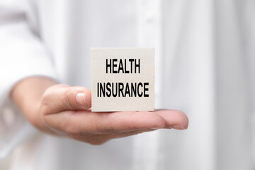 Text Health Insurance written on cube in hahd of female doctor, medical concept.