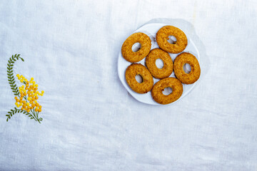 bizcochos con cereales artesanales hechos en casa en plato de ceramica blanco sobre mantel blanco