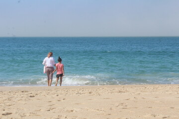 mother and daughter walking on the beach