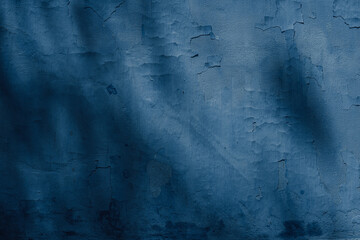 Dark blue rough surface, textured wall covered with old falling down plaster. With spots of shadows and light