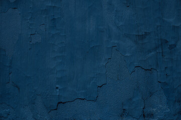 Dark blue rough surface, textured wall covered with old falling down plaster. 