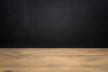Empty wooden table over black textured chalkboard for product display