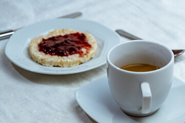 still life con taza de cafe y bizcocho de arroz con mermelada de ciruelas sobre mantel blanco