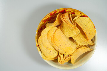 full bowl of yellow potato chips on gray background