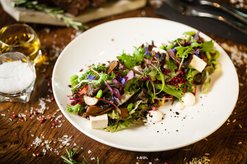 Fresh vegan salad. Avocado, couscous, melon, portobello, soybean, tofu on white plate. Delicious healthy mixed greens food closeup served on a table for lunch in modern cuisine gourmet restaurant.