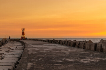 Fantastic sunsets over the Atlantic Ocean, while a group of fishermen fish by the lighthouse.