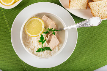 Chicken soup with lemon, egg yolks, parsley and rice. High key. Green background.