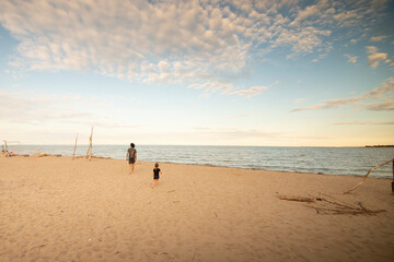 Father and child walking in the distance at Porto Caleri coastal botanical garden and wild beach at sunset, Veneto, Italy.