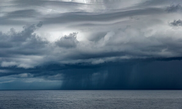 Heavy rainy clouds pouring rain over the ocean