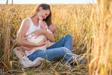 Naklejka na ściany i meble Beautiful young mother and her baby girl at the wheat field in sunny day, Czech republic