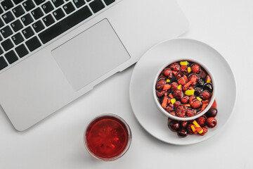 Fruit salad and juice with laptop on white background. Healthy breakfast concept.