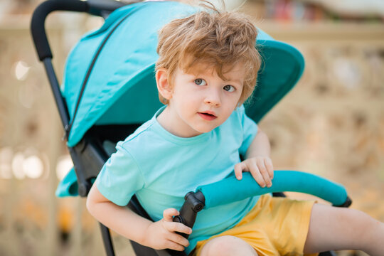 little boy of two years sits in a blue stroller in the summer. child development. Children's Lifestyle