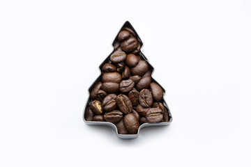 Brown coffee beans filled into a Christmas tree shaped cookie cutter on white isolated background, glossy surface