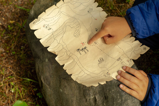 The child's hand points to the place of the treasure on the map of the treasure island