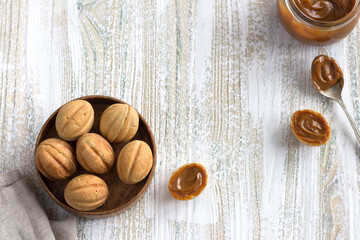 Traditional Russian  shortbread nuts with boiled condensed milk in a wooden bowl on a wooden background
