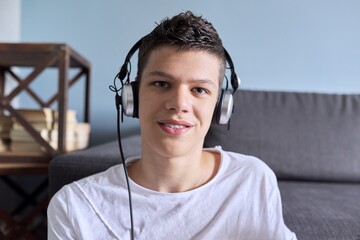 Portrait of student boy teenager in headphones looking at webcam, videocall