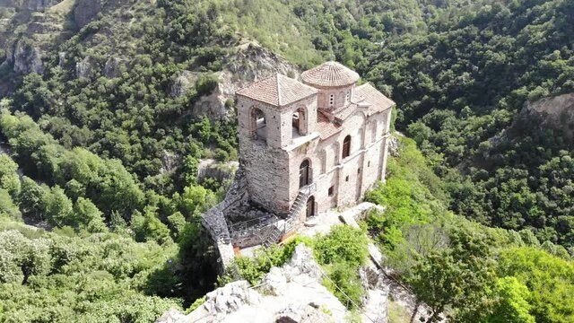 Medieval Fortress on a hill in eastern Europe, Bulgaria. Bulgarian antique and heritage stronghold fortification on a rock. Aerial video of a holy place and monastery. Tourist place with forest. Drone
