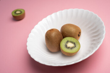 Kiwis on white bowl over pink table and half blurred