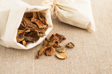Dried mushrooms in a canvas bag on a burlap background. Organic, eco-friendly food