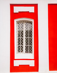 Ancient white cathedral's window with a lattice in red wall. Church window in a classical style. Bright part of old building. Exterior of Sretensky Church in Dmitrov