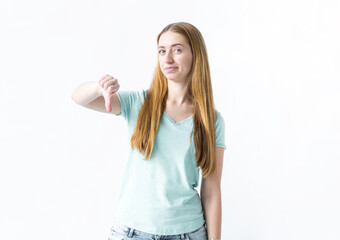 Beautiful girl in t-shirt showing thumb down gesture over white background